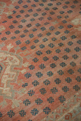 Vintage distressed Oushak carpet close-up with pale blush field, teal germinating motifs, and soft wear.