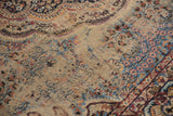 Vintage Malayer carpet's scalloped millefleur pattern on a worn beige field.