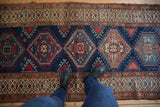 Repeating geometric medallions, hook-and-latch, and pinwheel motifs on a navy vintage rug.