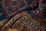 Folded Northwest Persian runner displaying geometric hook-and-latch motifs in navy and red.