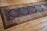 Madder root red and ivory borders with hook-and-latch motif framing the navy field of a vintage Persian runner.