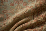 Textured folds of the distressed Heriz runner, revealing muted green and rust Herati pattern.