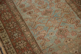 Distressed vintage Heriz rug with visible wear, Herati motif, and abrashed blue-green field.