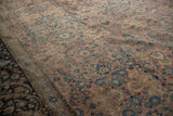 Angled view of a distressed Tabriz carpet's low pile, showing the blush field and dark navy border.