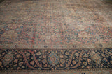 Low-angle view down the length of a distressed Tabriz carpet, contrasting the dark navy border with the soft blush field.