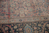 Angled view showing the time-softened texture and navy floral border of a vintage Tabriz carpet.