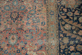 Close-up of a Tabriz carpet's distressed texture showing raspberry florals and a dark navy border.
