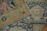 A small visible repair on the distressed, low pile of the vintage hand-knotted Tabriz carpet.