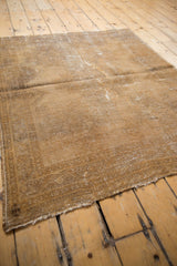 Distressed vintage Afshar rug corner, revealing foundation and muted beige-gold pattern.