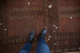 Wine red antique Turkmen carpet showing germinating plant motifs, rams horn borders, and repairs.