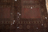 Antique Turkmen carpet detail: burgundy and oxidized silver geometric patterns, starburst guls, and storied wear.