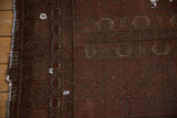 Detail of antique Turkmen carpet, wine red field, time-softened geometric patterns, and visible repairs.