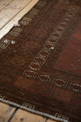 Antique Turkmen carpet with wine red field, ivory starburst, and ram's horn border motifs.
