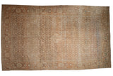 A vintage distressed Tabriz carpet with a dense Herati motif and wide border in muted sand and ivory tones.
