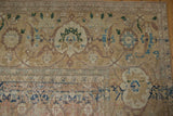 The wide-banded samovar border and abrashed Herati field of a distressed vintage Tabriz carpet.