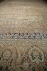Angled view of a vintage Tabriz carpet showing time-softened wear and its navy samovar border motifs.