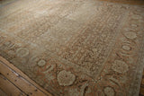 Angled view of a distressed Tabriz carpet's wide samovar border and evenly worn, low pile.