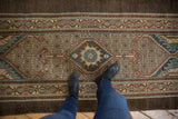 Distressed Serab runner rug with a central blue medallion and intricate lattice pattern.