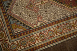Intricate geometric borders with red and blue patterns on distressed ivory Serab rug.