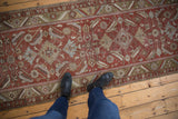 Vintage distressed Heriz runner with faded brick red field and prominent Herati pattern.