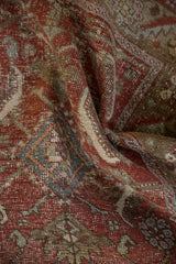 Distressed Heriz rug's worn pile, featuring brick red, olive, and powder blue Herati motif.