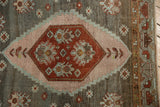 Distressed Malayer rug detail: rust geometric medallion, blush stepped border, floral motifs.