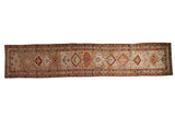 Distressed Northwest Persian runner rug with central geometric medallions in madder root red and ivory.
