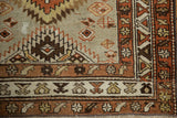 Northwest Persian rug with serrated border and pinwheel motifs in worn red, silver, and brown.