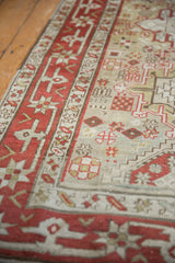 Angled view of the distressed Karaja rug's low pile and geometric motifs in red, sage, and beige.