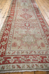 Perspective view down the length of a vintage Karaja runner with time-softened red and beige geometric medallions.