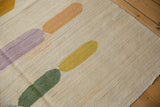 Abstract elongated pebble design in lilac, olive, saffron, and gold on ivory kilim.