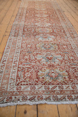 Angled view down a distressed Karaja runner showing its allover palmette and vinery pattern.