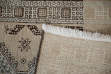 Distressed beige Serab runner close-up showing worn pile, geometric motifs, foundation, and white fringe.
