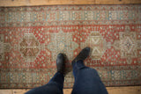 Distressed vintage Heriz runner with geometric medallions and pinwheel motifs on pale brick.