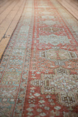 Distressed Heriz runner with blush, beige, and faded blue geometric medallion relief.