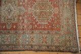 Distressed vintage Heriz runner corner with pale brick red field, geometric borders, worn fringe.