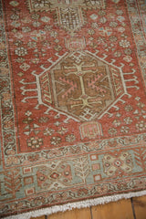 Distressed Heriz runner's worn pile, fringe, and geometric border in dusty rose, muted teal.