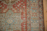 Distressed Heriz runner close-up, showing pale blue geometric border and faded red field with floral motifs.
