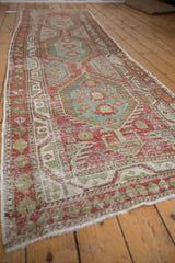 Angled view of a distressed Heriz runner with faded red and blue geometric medallions.