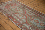 Repeating medallions and low-pile texture along the length of a distressed vintage Heriz runner.