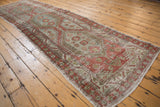 Angled view highlighting the slight natural bow of a vintage distressed Heriz runner.