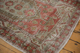 Character-rich wear on the corner of a vintage Heriz rug in dusty red and pale slate.