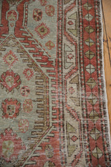 Worn border of a distressed Heriz runner with pinwheel motifs in pale slate and dusty red.