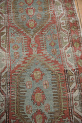 Distressed wear reveals knot heads on a vintage Heriz runner with finned geometric medallions.