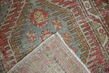 Folded corner of a distressed Heriz rug reveals the hand-knotted foundation and worn pile.