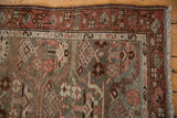 Distressed Hamadan runner corner, showing faded red geometric border and dusty blue, worn pile.