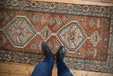 Distressed vintage Northwest Persian runner with dusty brick-red, pale blue, and ivory medallions.
