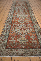 Distressed Northwest Persian runner detail: dusty brick red field, pale blue serrated medallion, tribal motifs.