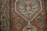 Distressed Northwest Persian rug close-up: serrated motifs, brick red, pale blue, and ivory tones.
