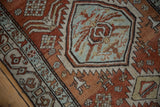 Distressed Northwest Persian rug detail: serrated medallion, floral, plants in brick red, pale blue.